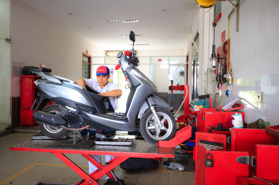 Mekanik menservis motor matic di atas lift
