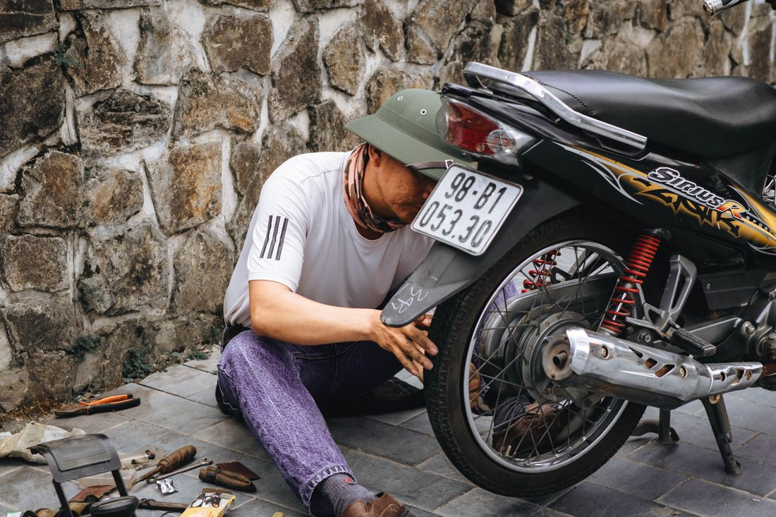 Montir menambal ban belakang motor